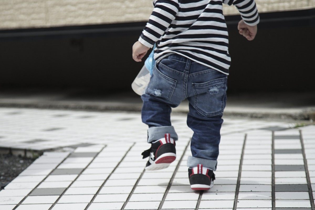 A young boy riding a skateboard down a sidewalk